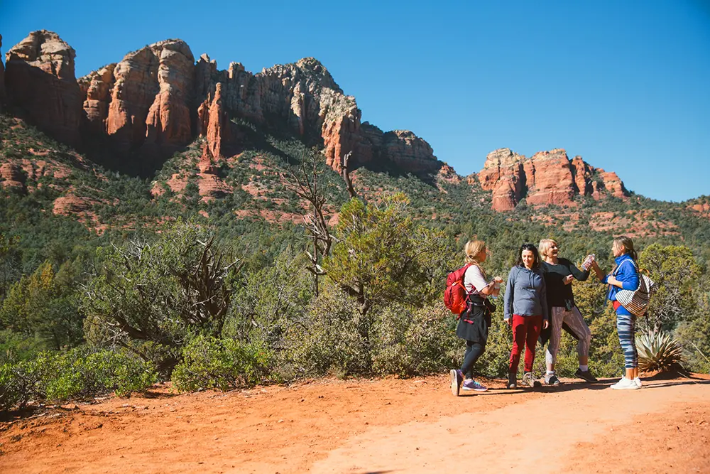 Four women hiking on a red rock trail during a Sedona Vortex Adventures Root Chakra ceremony