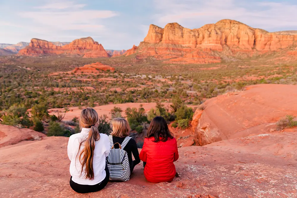 "Three clients enjoying the expansive red rock views during a Sedona Vortex Adventures guided hiking tour.